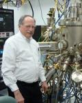 Dr Brueck next to a complex vacuum chamber