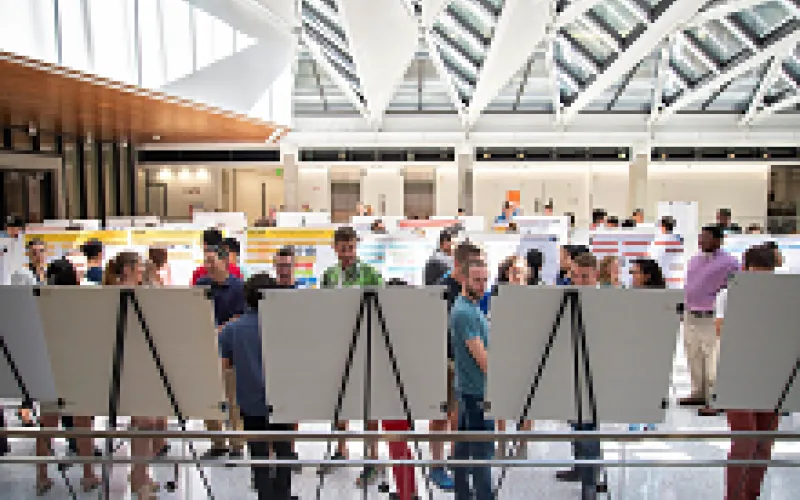 Students in EER building atrium, sharing research posters